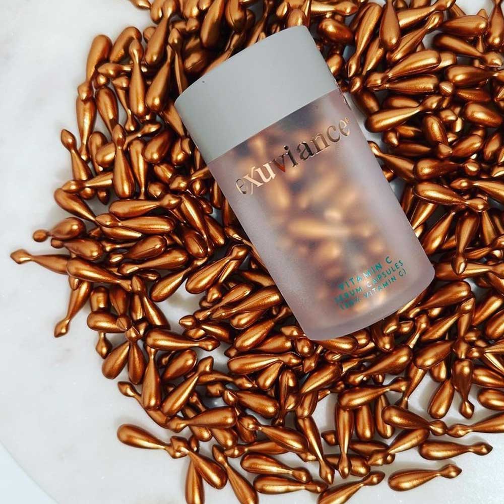 Exuviance Vitamin C 20% Serum capsules displayed with minimalistic design for anti-aging skincare.